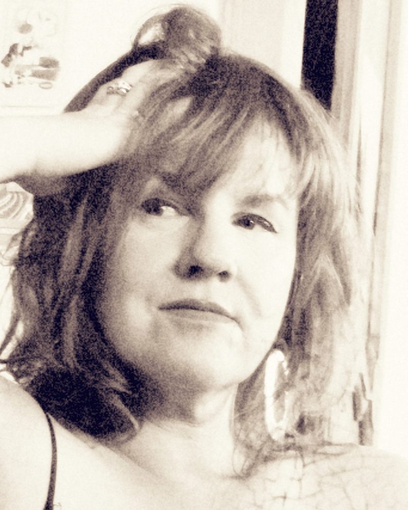 Portrait en noir et blanc de Laure, la Confidente, la main posée dans les cheveux, regard tourné vers l'objectif.
